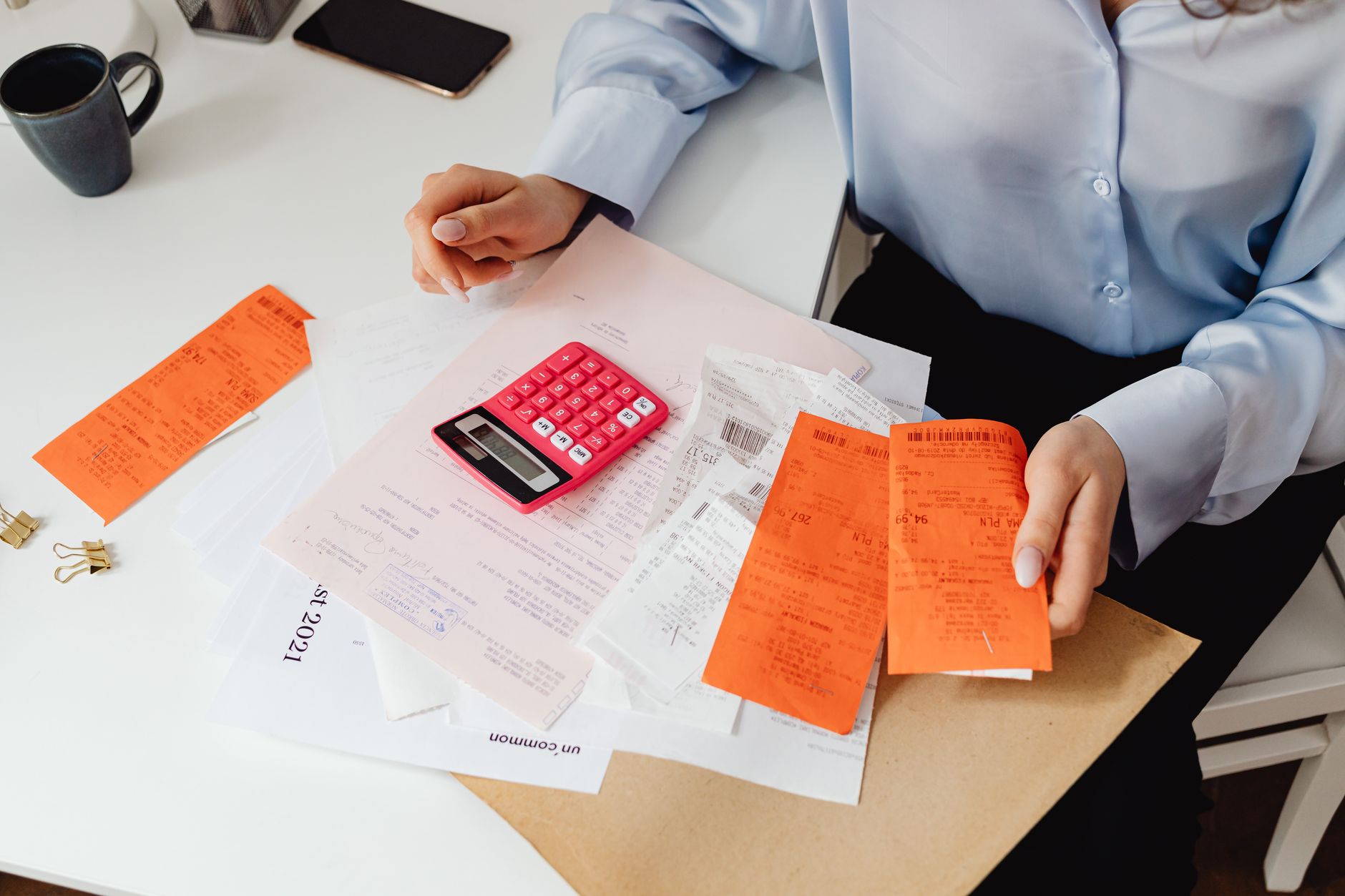 Person photographing a paper receipt with a smartphone at an office desk