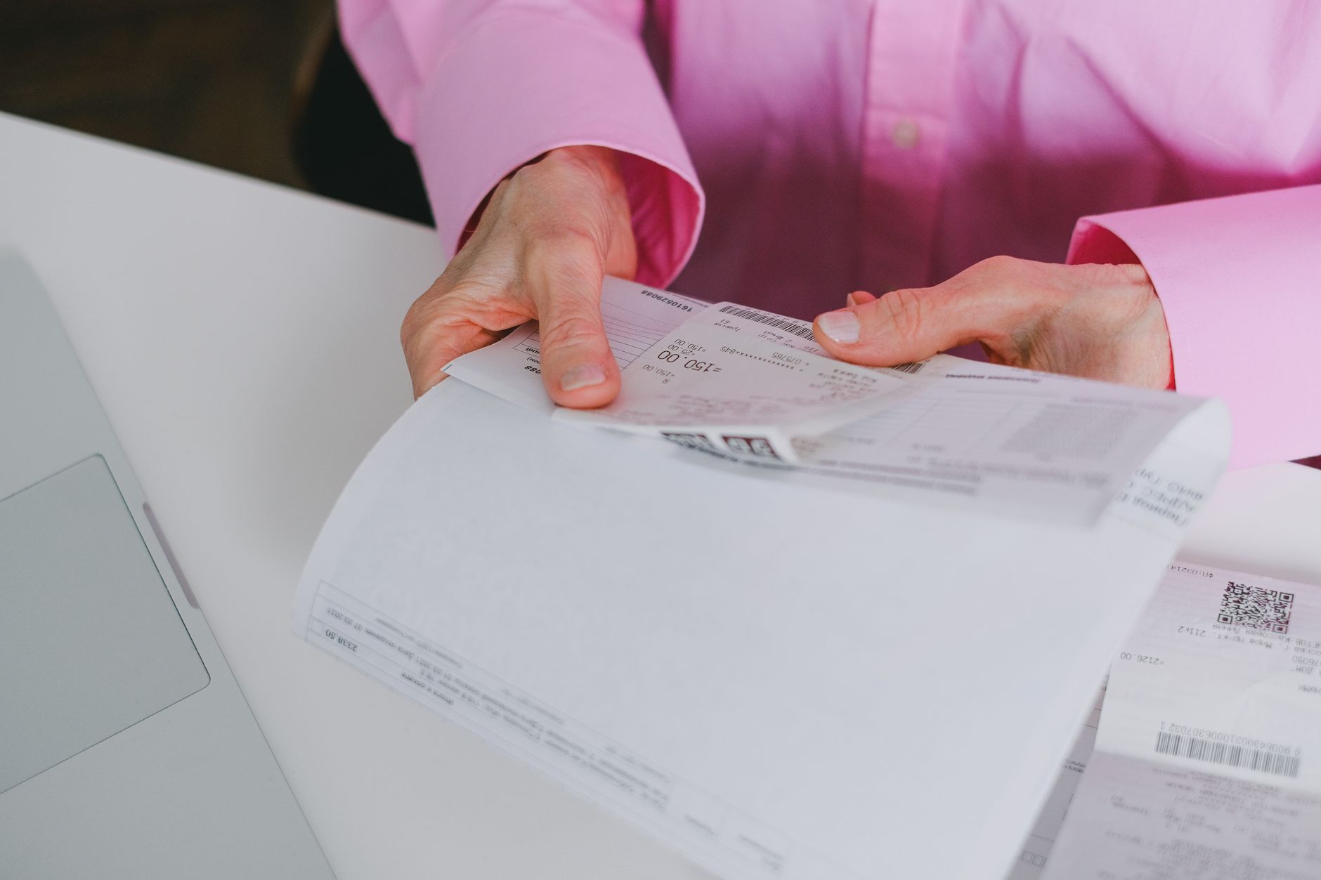 Business person holding a corporate credit card while reviewing a laptop at a desk