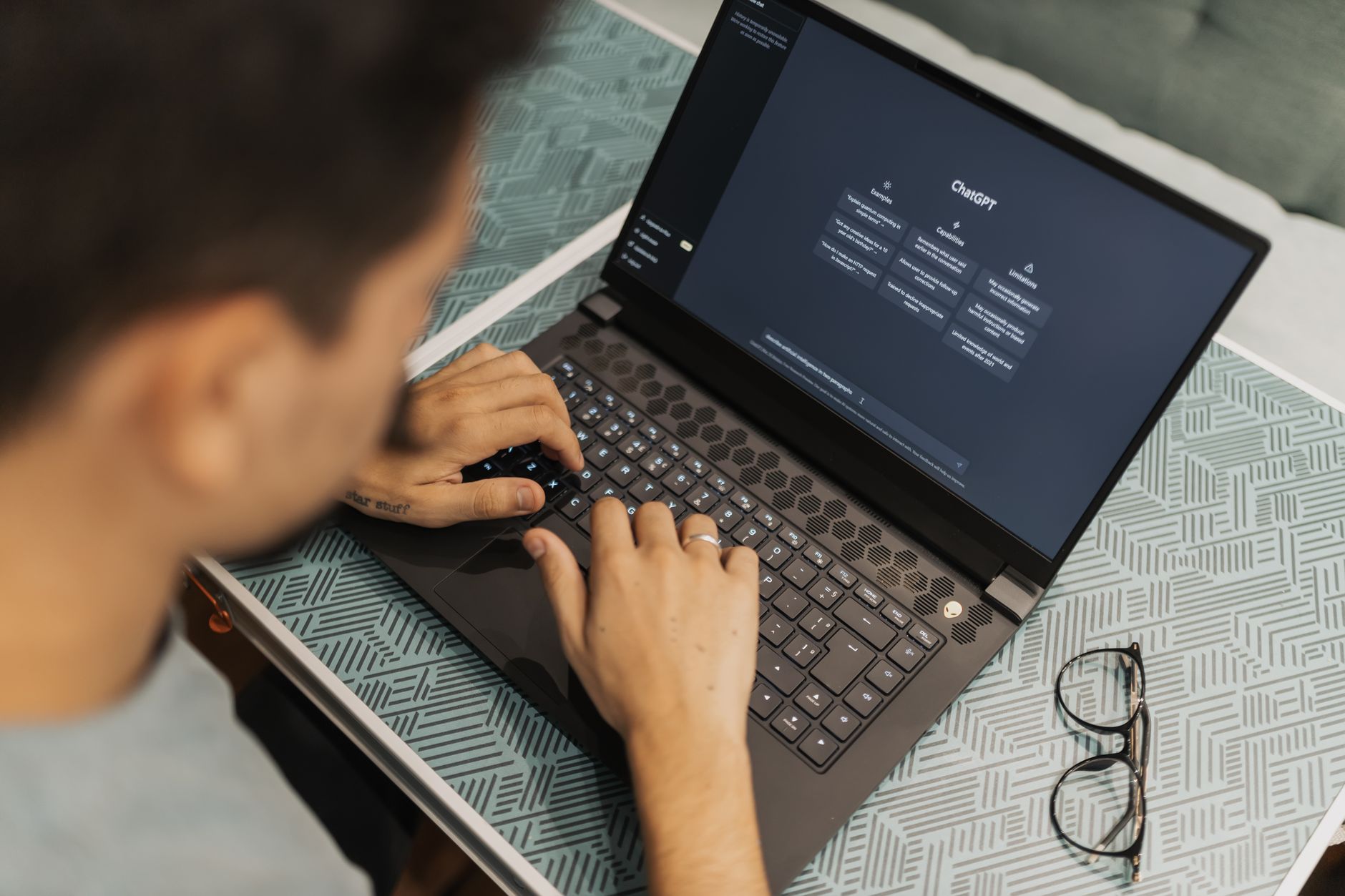 Person chatting with an AI assistant on a laptop while writing notes